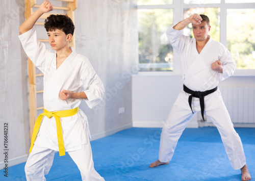 Active teenage male attendee of karate classes practicing kata in sports hall