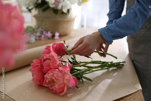 Florist making beautiful peony bouquet at table, closeup © New Africa