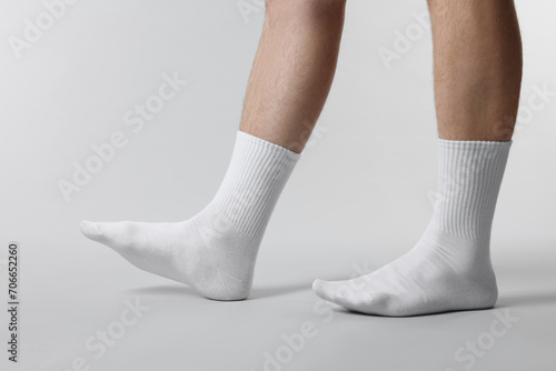 Man in stylish white socks on light grey background, closeup