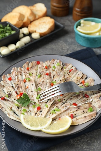 Tasty pickled anchovies with spices and fork on grey table