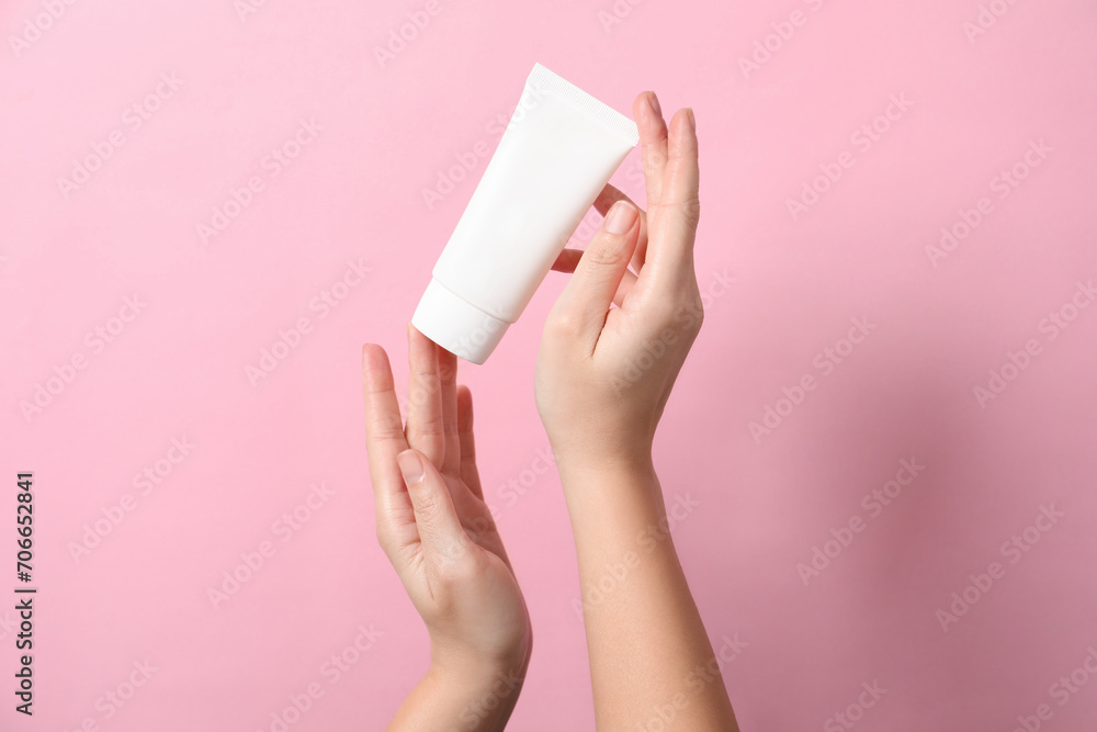 Woman with tube of hand cream on pink background, closeup Woman with tube of hand cream on pink background, closeup
