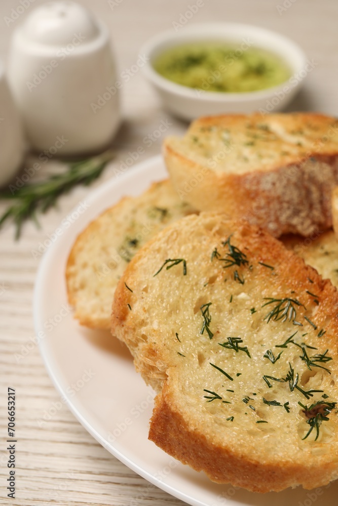 Tasty baguette with garlic and dill on white table, closeup Tasty baguette with garlic and dill on white table, closeup
