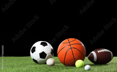 Many different sports balls on green grass against black background  space for text