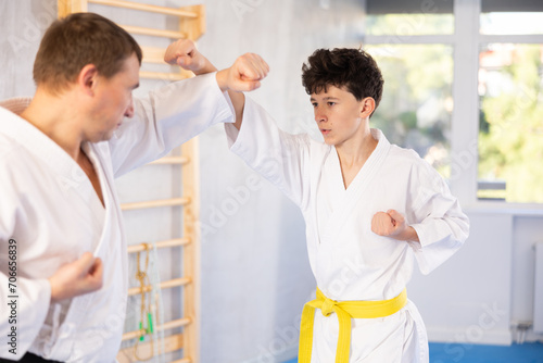 Adult man and teenage boy karatekas training karate fight in studio