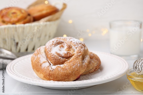 Delicious roll with sugar powder on white tiled table, closeup. Sweet bun