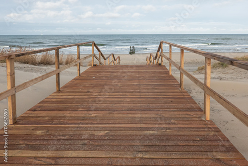 Descent to the sea along a wet wooden deck. In the background you can see the Baltic Sea and a deserted winter beach. Scenery.