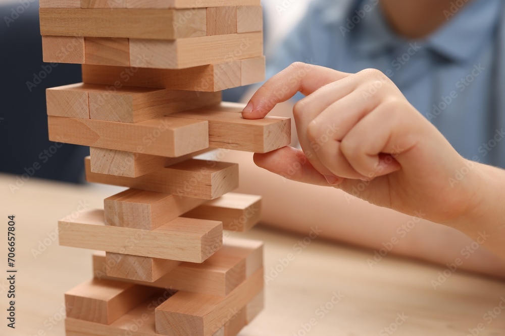 Child playing Jenga at wooden table indoors, closeup Child playing Jenga at wooden table indoors, closeup