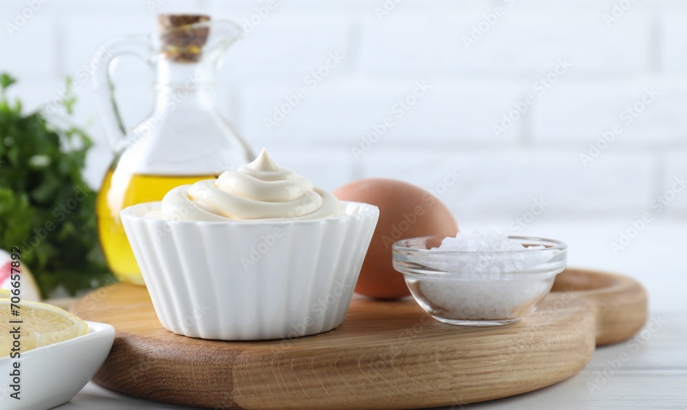 Fresh mayonnaise sauce in bowl and ingredients on table