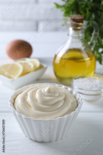 Fresh mayonnaise sauce in bowl on white wooden table