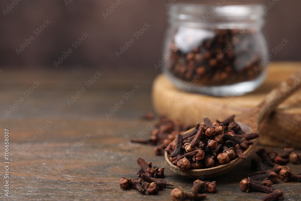 Spoon with aromatic cloves on wooden table, closeup. Space for text Spoon with aromatic cloves on wooden table, closeup. Space for text