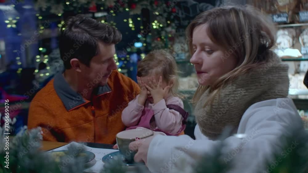 Family with toddler drinking hot chocolate and cocoa in the cafe after Christmas market. Leisure activity on holidays with family. Family with toddler drinking hot chocolate and cocoa in the cafe after Christmas market. Leisure activity on holidays with family.