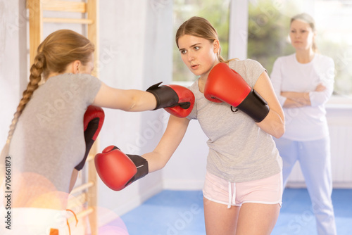 Two teen girls in punch mitts boxing in gym © JackF