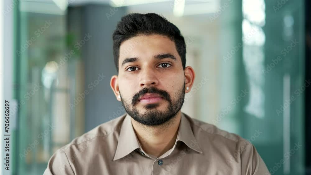 Portrait of a serious bearded entrepreneur in a shirt sitting at workplace in a business office. Confident successful businessman posing looking at the camera. Head shot of handsome employee. Close up Portrait of a serious bearded entrepreneur in a shirt sitting at workplace in a business office. Confident successful businessman posing looking at the camera. Head shot of handsome employee. Close up