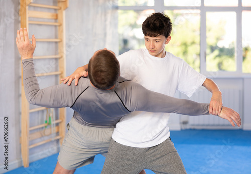 Adult man and boy teenager training self-defense techniques in studio