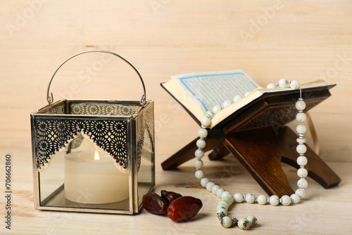 Tableau sur toile Muslim lamp with burning candle, dates, Koran and prayer beads on light wooden b