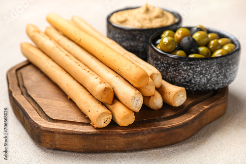 Wooden board with tasty Italian Grissini on light background, closeup