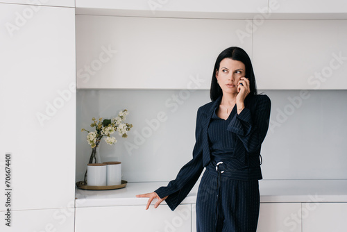 Concerned business consultant in a navy blue pinstripe suit engages in a serious conversation over the phone in a sleek, white minimalist office. photo