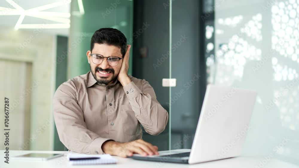 Earache. Sick businessman suffers from ear pain while working on laptop sitting in office. Upset male touches his ear with his fingers. He has furuncle, shingles, eczema, ear diseases or otitis media Earache. Sick businessman suffers from ear pain while working on laptop sitting in office. Upset male touches his ear with his fingers. He has furuncle, shingles, eczema, ear diseases or otitis media