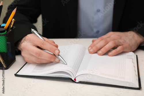 Man taking notes at white wooden table, closeup