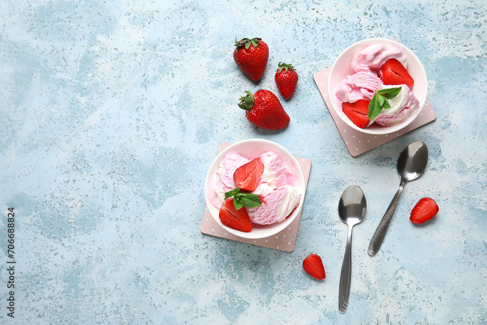 Bowls of strawberry ice cream and spoons on grunge background