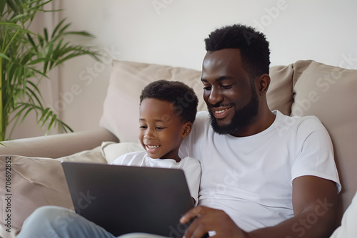 Young black father and kid son using laptop at home for child education looking at pc screen, smiling african dad and toddler boy study learning computer, watching video
