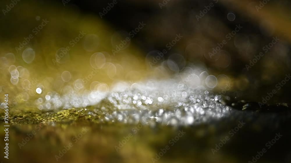 Bokeh of a moutain stream flowing in summer sunlight in slow motion Bokeh of a moutain stream flowing in summer sunlight in slow motion