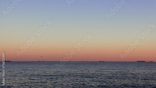 Sunset over calm sea, ships on roadstead bask in sunset glow. Tranquil sea waves at sunset, ships anchored in roadstead. Roadstead ships illuminated by sunset, calm sea waves photo