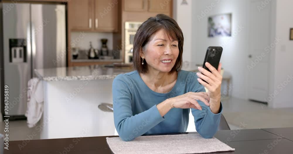 Cheerful attractive woman smiling enjoying video chat laughing talking using mobile phone relaxing at home kitchen table. Cheerful attractive woman smiling enjoying video chat laughing talking using mobile phone relaxing at home kitchen table.