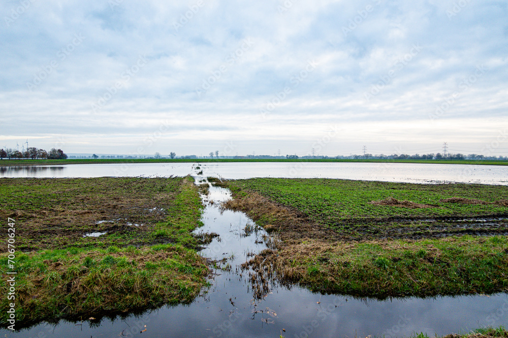 Hochwasser - nach starken Regenfällen überflutete Ackerfläche, mit Spaten ausgehobene Enwässerungsrinne.