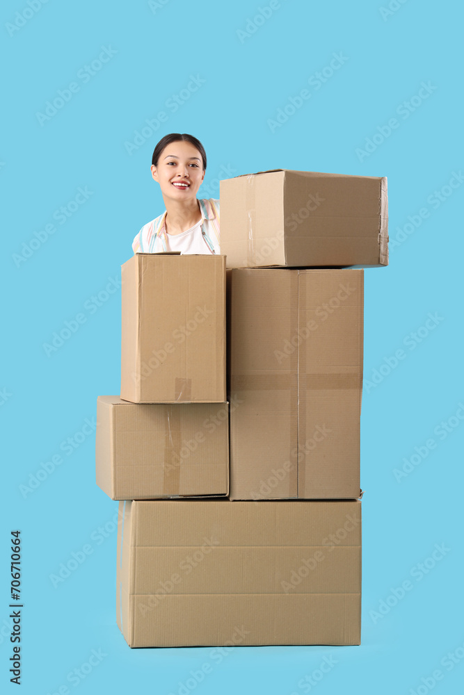 Young Asian woman with parcels on blue background