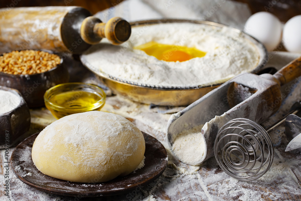 Fototapeta premium The process of kneading dough in the kitchen. Eggs, flour and other ingredients on the kitchen table in a composition.