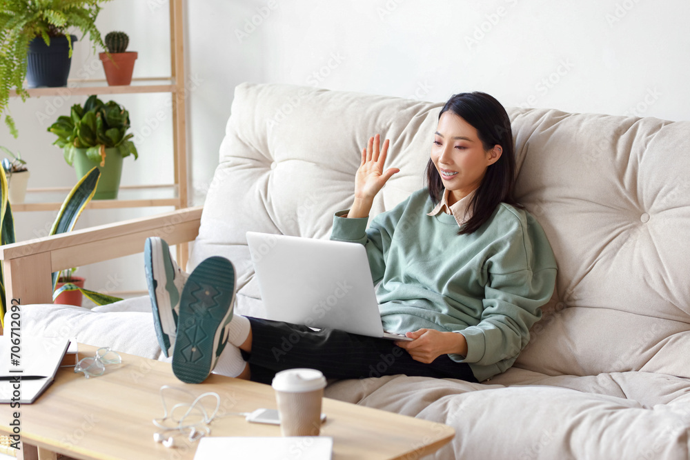 Young Asian woman with laptop video chatting at home Young Asian woman with laptop video chatting at home