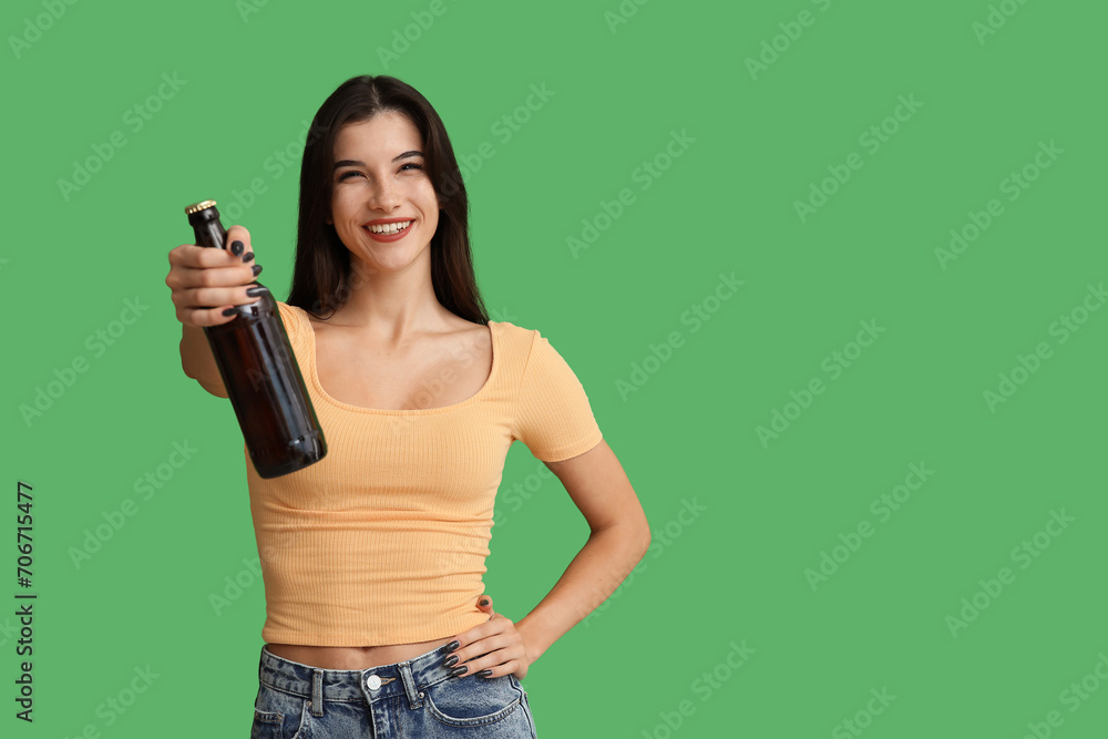 Beautiful young woman with bottle of cold beer on green background