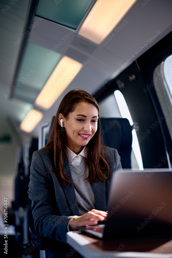 Happy businesswoman working on computer while traveling by train. Happy businesswoman working on computer while traveling by train.