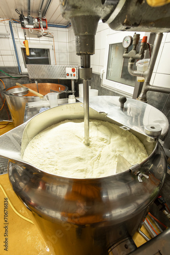 A cheese maker oversees the curdling milk in a large stainless steel vat during the cheese-making process photo