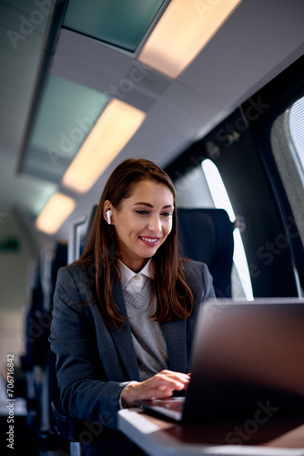 Happy businesswoman working on computer while traveling by train. © Drazen