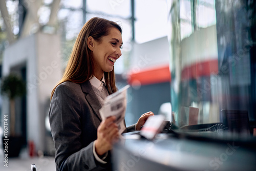 Cheerful woman buying travel ticket at train station. photo
