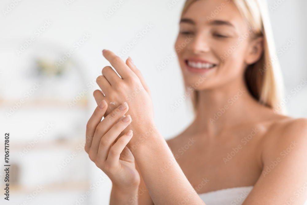 blonde woman gently rubbing moisturizer on her hands in bathroom blonde woman gently rubbing moisturizer on her hands in bathroom
