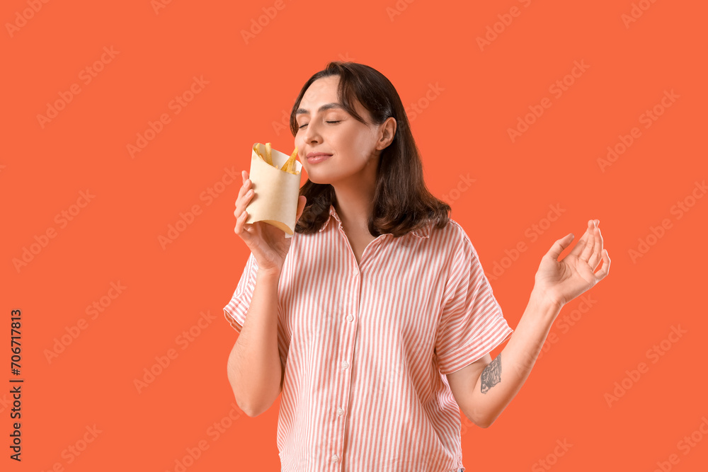 Young woman with french fries on orange background Young woman with french fries on orange background