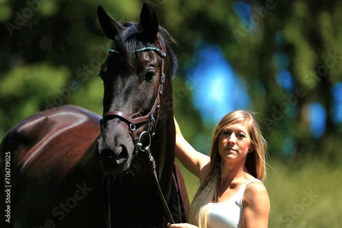 Woman young blonde long hair on a meadow in summer with horse.