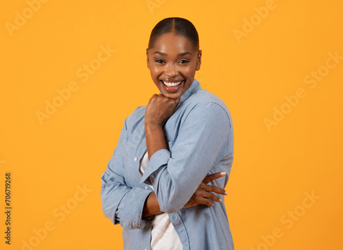 Black millennial lady standing touching chin with cheerful smile  studio