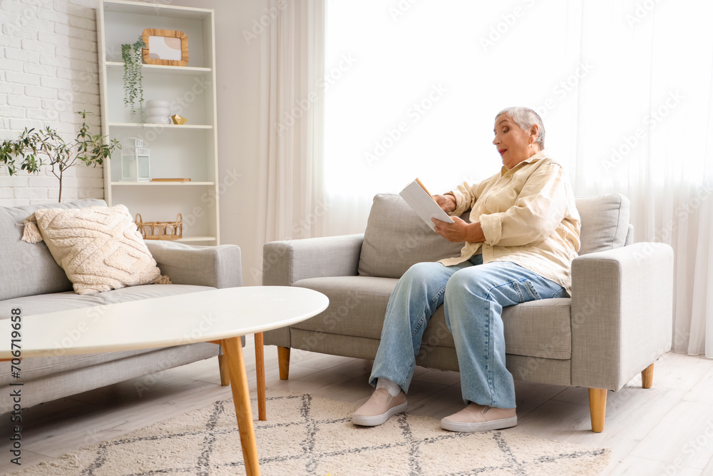 Senior woman reading book on sofa at home Senior woman reading book on sofa at home