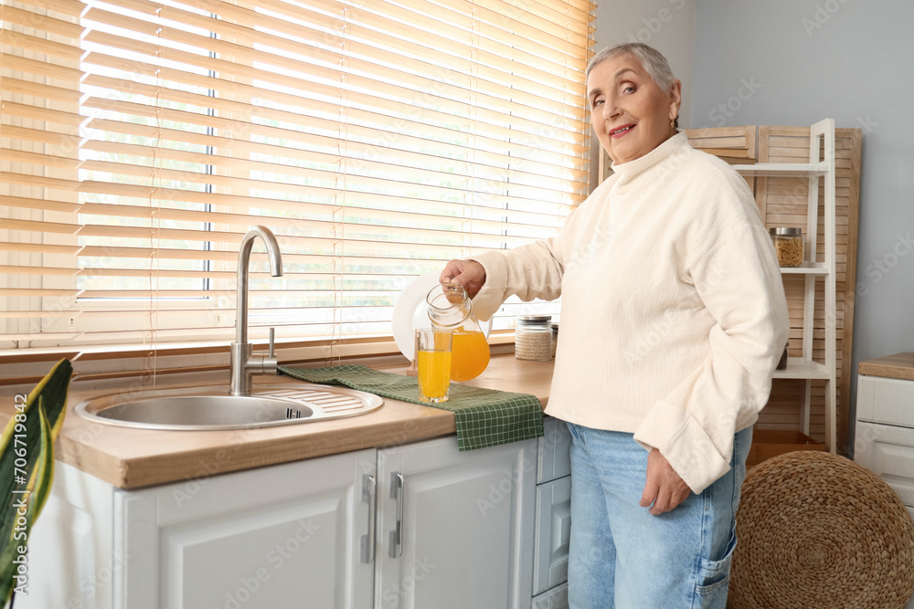 Senior woman pouring juice in kitchen Senior woman pouring juice in kitchen