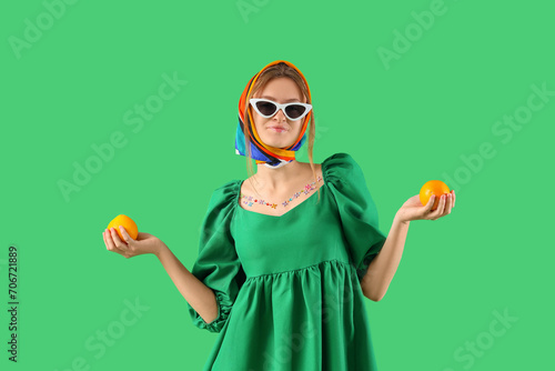 Pretty young woman with oranges on green background photo