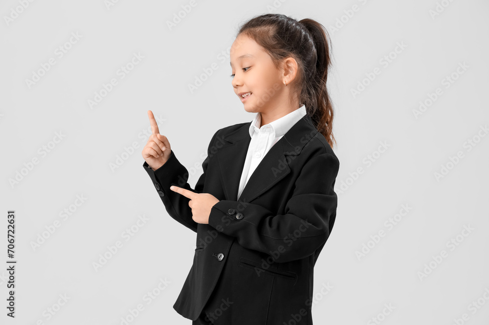 Cute little businesswoman pointing at something on light background. Opposite Day celebration Cute little businesswoman pointing at something on light background. Opposite Day celebration
