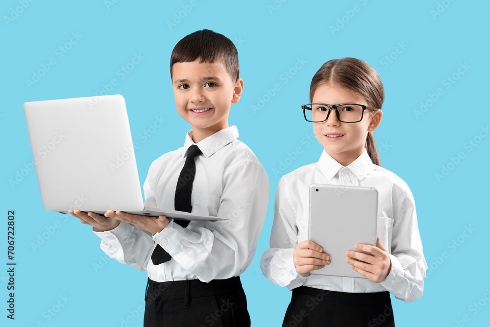 Little business colleagues with laptop and tablet computer on blue background. Opposite Day celebration