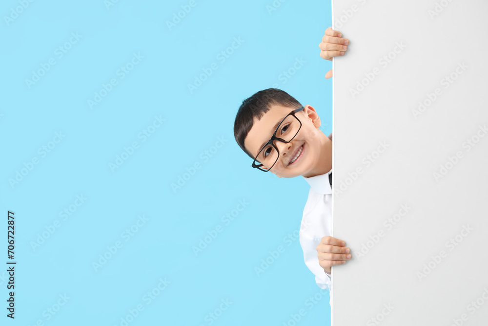 Cute little businessman with blank poster on blue background. Opposite Day celebration Cute little businessman with blank poster on blue background. Opposite Day celebration