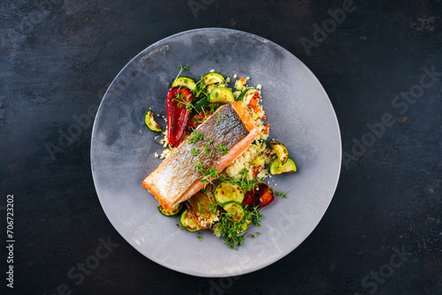 Traditional Mediterranean salmon fish fillet with vegetable cuscus served as top view on a design bowl with copy space