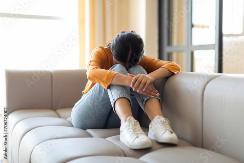 Upset indian woman sitting on couch with her head down