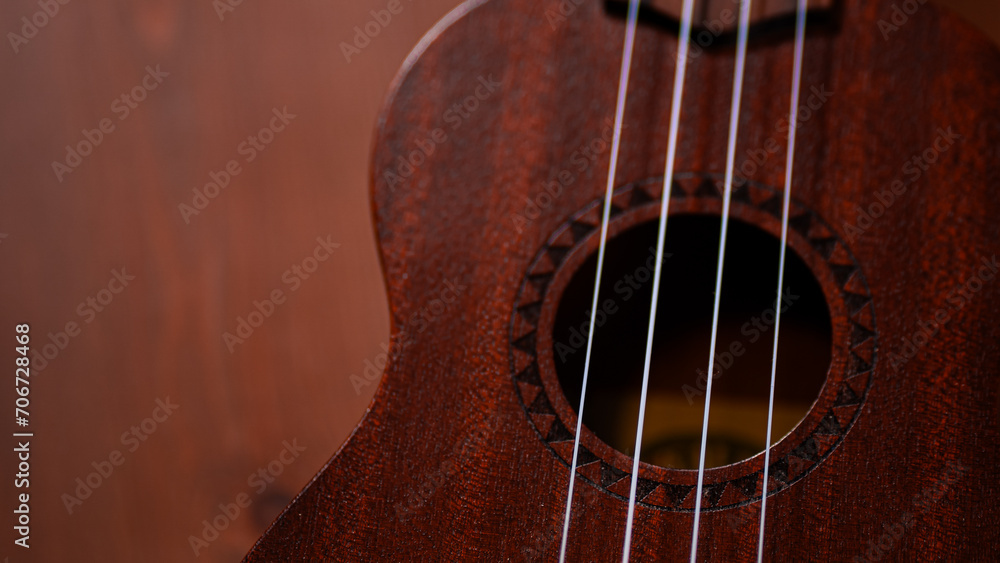 A charming ukulele gracing a wooden table, inviting musical moments with its acoustic allure and strings that resonate with a touch of Hawaiian serenity A charming ukulele gracing a wooden table, inviting musical moments with its acoustic allure and strings that resonate with a touch of Hawaiian serenity